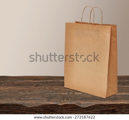 Blank paper craft shopping bag on wooden table with copyspace