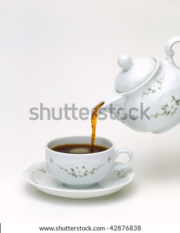 Tea pouring into glass cup isolated in white