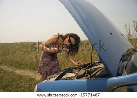 young woman making a funny face while trying to fix a broken car