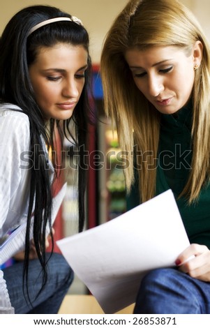 Two students learning together in the university corridor before an exam