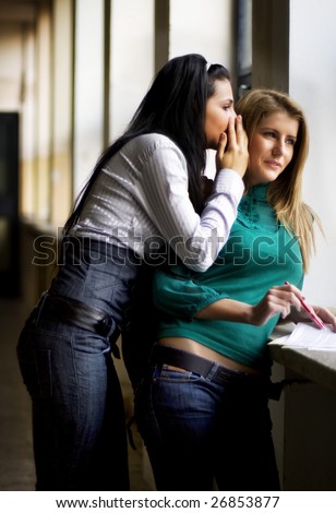 Young woman whispering a secret to the ear of another young woman