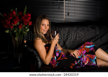 Young Woman Lounges on Couch drinking a Glass of Wine