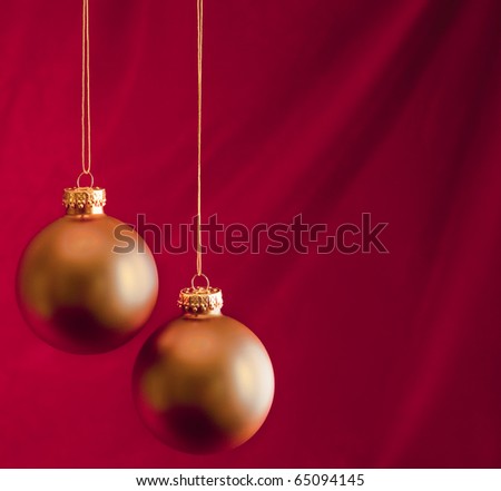 Two Gold Ornaments on Red Velvet Background