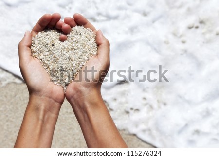 Mellow heart shaping female hands above beach Mellow heart shaping female hands above beach