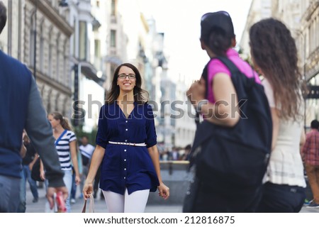 Cheerful urban girl standing out from the crowd at a city street.