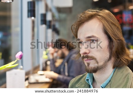 Real People - Portrait of a pensive and handsome young man in coffee shop with available light.