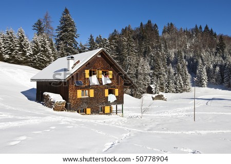 Winter vacation - Rural sunny winter landscape with occupied chalet.