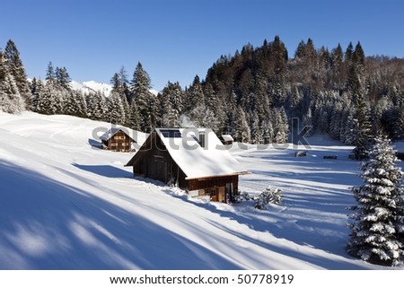 sunny winter landscape with occupied and heated log cabins in the mountains.