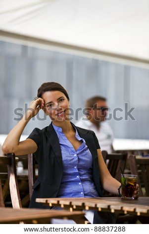 Pretty and young woman sitting in a garden of a restaurant and enjoys her break from work.
