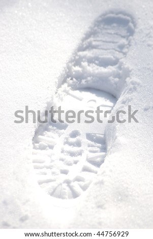 child\'s snow boot footprint in the white snow