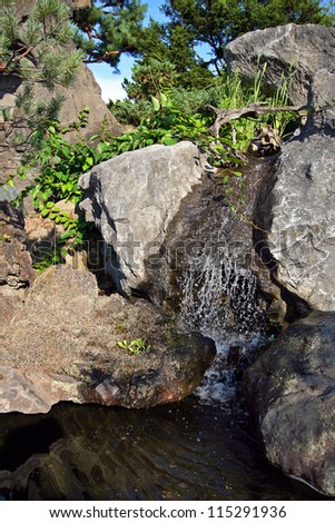 Small waterfall among the rocks in japanese garden.