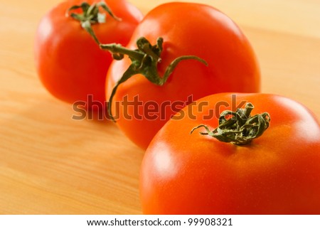 Three tomatoes on a cutting board.
