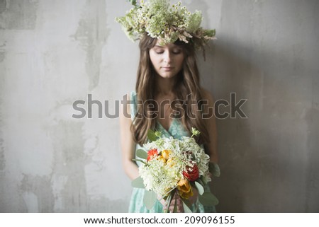 beautiful girl, brunette with a bouquet of flowers and a wreath in her hair