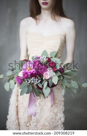 Luxury bride in a pink dress with a wedding bouquet in the wine color