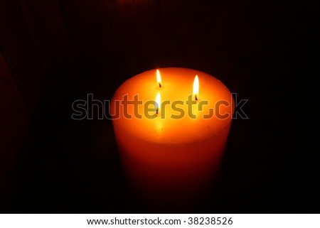 large candle  with 3 flames burning