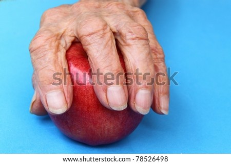 wrinkled hands of an old woman holding an apple