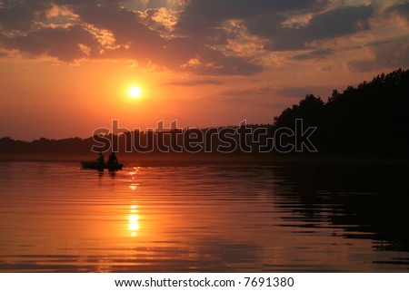 Two (2) men fishing in a boat in lake during sunset. Geographical location: Europe