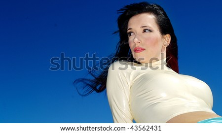 A sexy woman wearing white and blue latex standing against a bright blue sky