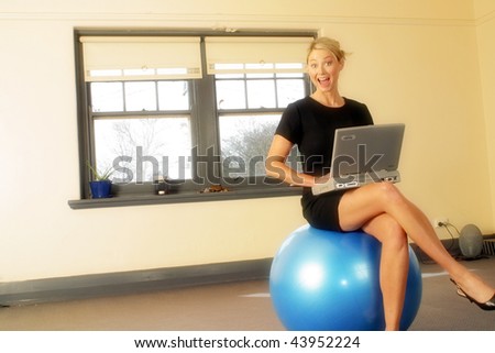A modern 30s woman sitting on Fitness ball in empty apartment using laptop computer  She is dressed in corporate attire Photography