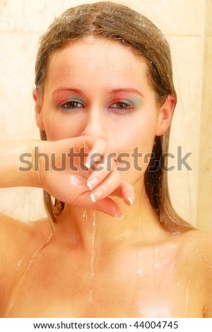 20s woman in shower with water flowing over her face hand across mouth looking at the camera
