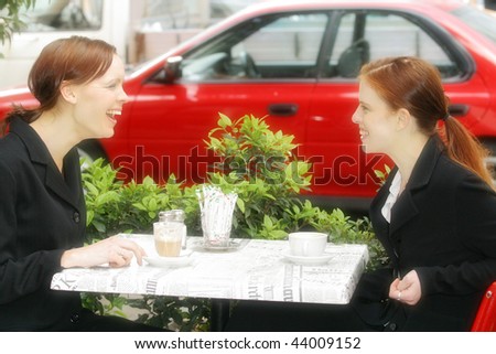 Two young Australian woman sitting at a cafe happy discussing and conversing