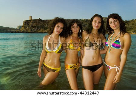 stock photo Four gorgeous young girls relaxing by the ocean during a hot 