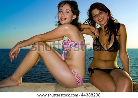stock photo Two gorgeous young girls relaxing by the ocean during a hot 