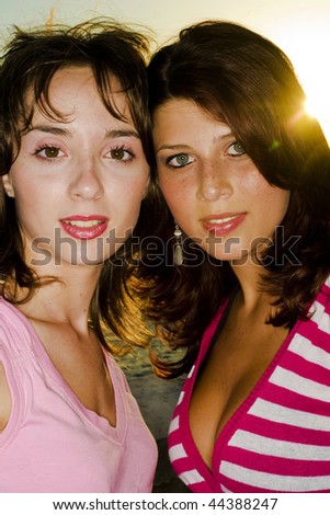stock photo Two gorgeous young girls relaxing by the ocean during a hot 