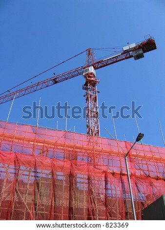 Crane in a building construction in red, with blue sky