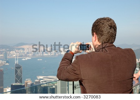 Tourist taking photo of Hong Kong skyline by his digital camera