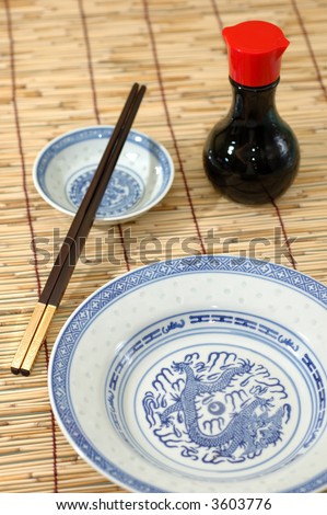 Chinese plate, chopsticks and soya sauce bottle on bamboo background