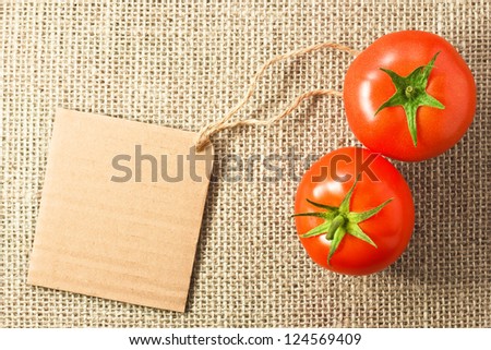 two tomatoes with cardboard tag on sacking