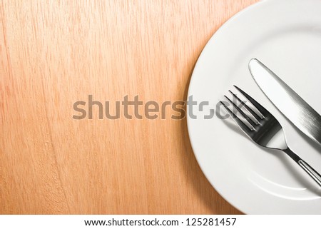 Photo of the fork and knife with white plate on wooden background Photo of the fork and knife with white plate on wooden background