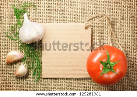 Photo of tomato and garlic vegetables and price tag on sacking background texture