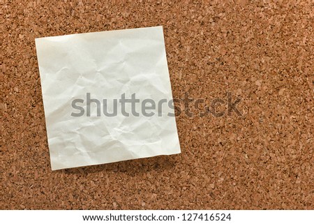 single blank crumpled white sticky note on a cork bulletin board
