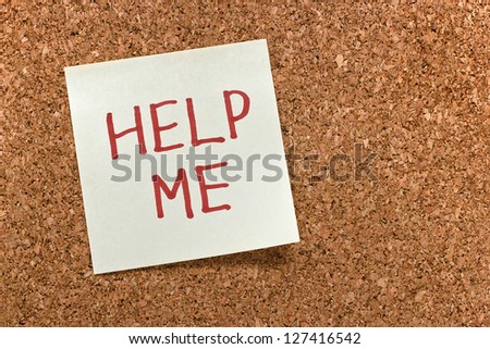 sticky note with help me text on a cork board background
