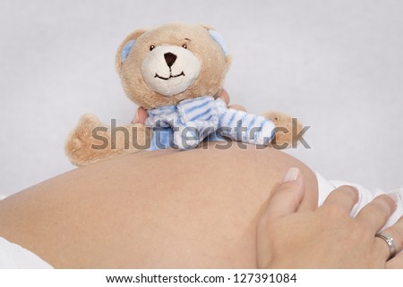 Baby belly of a reclining woman with small things stuffed bear