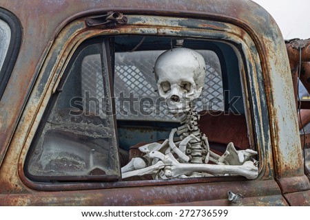 skeleton at the wheel of an old junk cars
