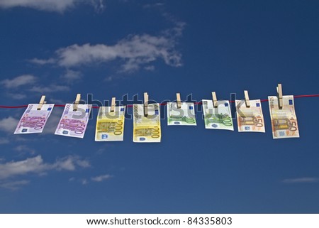 Bank notes fluttering on a clothesline against a blue sky in the wind