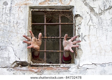 A pair of hands pleading for help at the prison window
