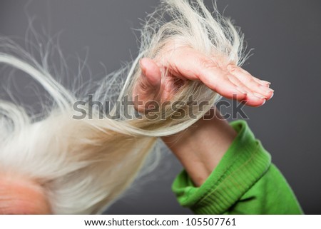 Closeup  of hand of senior woman in hair. Studio shot. Isolated on grey.