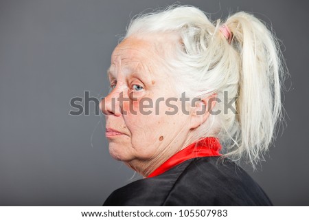 Senior woman with long grey hair wearing black and red kimono. Studio shot isolated on grey background.