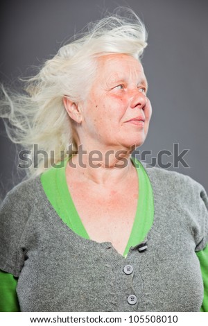 Studio portrait of happy senior woman with long hair in the wind. Studio shot isolated on grey background.