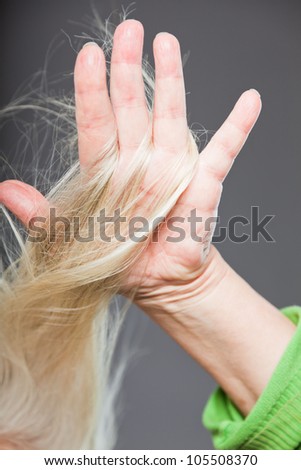 Closeup  of hand of senior woman in hair. Studio shot. Isolated on grey.