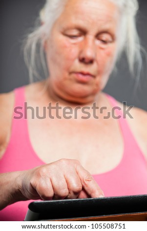 Senior woman holding tablet long grey hair. Studio shot. Isolated on grey background.