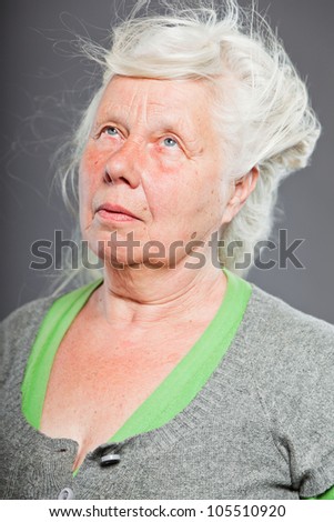 Studio portrait of happy senior woman with long hair in the wind. Studio shot isolated on grey background.