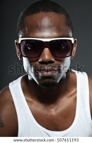 Cool urban stylish black american man. Fashion studio portrait isolated on grey background. Wearing dark sunglasses.