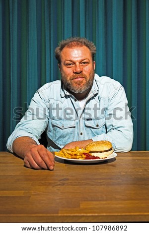 Man with beard eating fast food meal. Enjoying french fries and a hamburger.