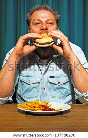 Man with beard eating fast food meal. Enjoying french fries and a hamburger.
