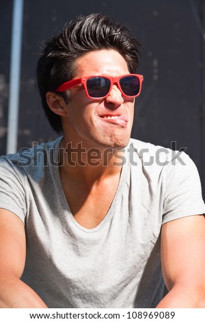 Urban asian man with red sunglasses making funny face. Good looking. Cool guy. Wearing grey shirt.